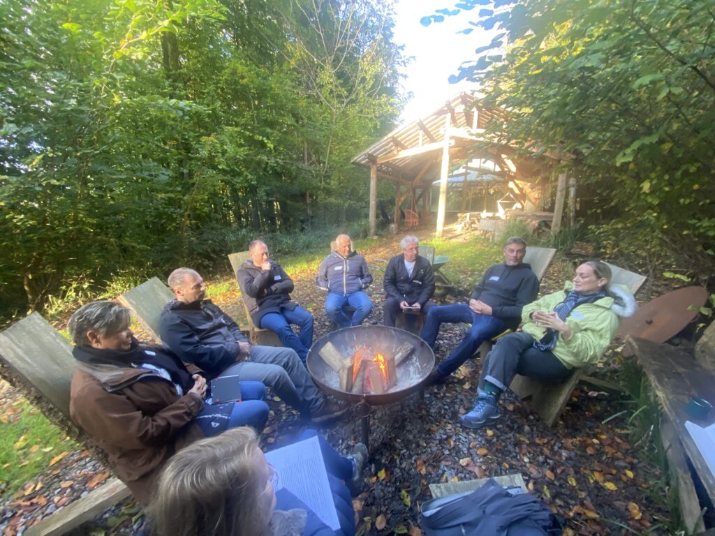 Leaders discuss and support each other in nature around a woodfire